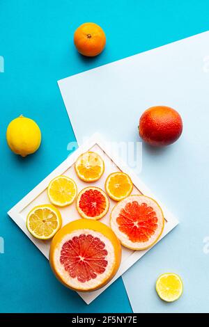 Minimale Stillleben von geometrischen Formen, Grapefruit, Zitrone, Orange und Mandarine auf blauem Hintergrund. Flach liegend mit Kopierplatz. Vegan, gesundes Essen Co Stockfoto