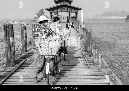 Zwei Frauen mit Fahrrädern über die U-Bein Brücke, Amarapura, Mandalay, Myanmar. Stockfoto