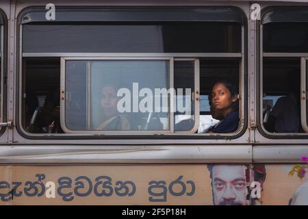 Weligama, Sri Lanka - März 28 2019: Einheimische srilankische Frauen machen Blickkontakt aus einem ÖPNV-Busfenster in Weligama, Sri Lanka. Stockfoto