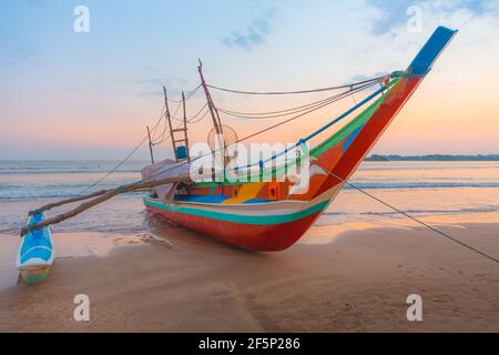Ein traditionelles Sri Lanka Angeln Katamaran Boot während eines bunten Sonnenaufgang oder Sonnenuntergang auf Weligama, Strand in Sri Lanka. Stockfoto