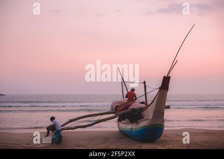 Lokale Sri Lanka Fischer bei Sonnenaufgang oder Sonnenuntergang Bereiten Sie sich auf Morgen oder Abend Angeln auf einem traditionellen Katamaran Boot von der Küste auf Weligama Beach, Stockfoto