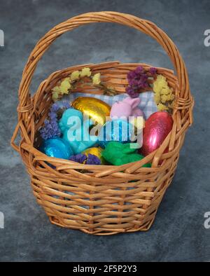 Korb mit ostereiern in farbiger Zinnfolie, Hasen und Blumen. Stockfoto