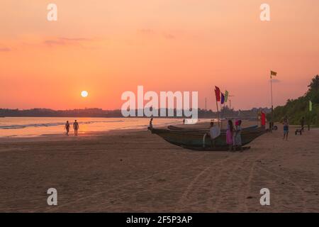 Weligama, Sri Lanka - März 27 2019: Einheimische und Touristen genießen einen orangefarbenen, goldenen Sonnenuntergang am Urlaubsort Weligama Beach an der Südküste o Stockfoto