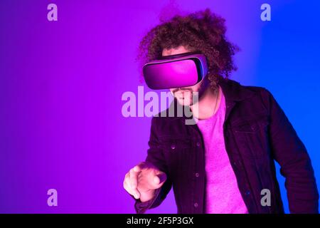 Afroamerikanischer Mann trägt Virtual-Reality-Headsets. Neonlicht Studio Porträt. Virtual Reality, Simulation, Spiel und Technologie-Konzept der Zukunft. Stockfoto