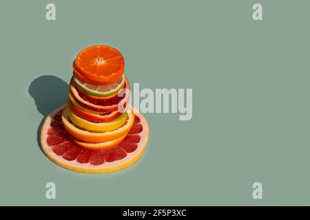 Ein Stapel von in Scheiben geschnittenen Zitrusfrüchten auf türkisfarbenem Hintergrund. Orange, Grapefruit, Limette, Mandarine, Zitrone. Bio-SPA-Kosmetik mit Orangenöl und Stockfoto