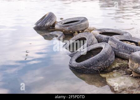 Alte Reifen am Strand. Verschmutzung des Reservoirs mit alten Autoreifen. Müll am Ufer Stockfoto