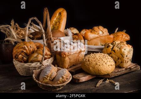 Stillleben von einer abwechslungsreichen Auswahl an Broten auf schwarzem Hintergrund, Backwaren Banner Stockfoto