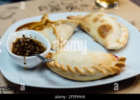 Argentinischer Kuchen mit würziger Sauce auf weißem Teller. Stockfoto