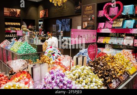 Moskau, Russland, Februar 2021: Im Lindt Schokoladenmarkt. Stapel von Süßigkeiten, Süßigkeiten, und Käufer im Inneren. Stockfoto