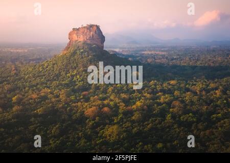 Dschungellandschaft Ansicht der alten Sigiriya Felsenfestung von Pidurangala Hill in Sri Lanka mit bunten Sonnenuntergang oder Sonnenaufgang Licht. Stockfoto