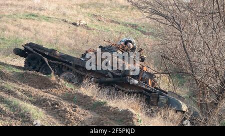 JABRAYIL, ASERBAIDSCHAN - DEZEMBER 15: Ein Mitglied der russischen Friedenstruppe untersucht einen zerstörten armenischen T-72-Panzer auf Überreste armenischer Kämpfer, die im Konflikt um die umstrittene Region Berg-Karabach am 15 2020. Dezember im Bezirk Jabrayil von Aserbaidschan getötet wurden. Ende September brachen schwere Zusammenstöße über Berg-Karabach aus, bei denen mehr als 5.600 Menschen, darunter auch Zivilisten, getötet wurden. Die Seiten einigten sich auf ein Waffenstillstandsabkommen, das am 10. November in Kraft trat Stockfoto