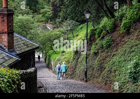 Ältere Freunde befahren den Kiesweg in Clovelly, einem kleinen Hafen und einem Dorf an einem Hang, das in der Zeit an der Küste von Nord-Devon verloren ging Stockfoto