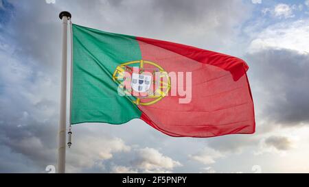 Portugal Zeichen Symbol. Nationalflagge der Portugiesischen Republik auf einem Pfahl, der vor wolkenverhangenem Himmel schwenkt. Stockfoto
