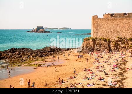 Der Strand und die Menschen Sonnenbaden unter den Stadtmauern, von der mittelalterlichen Festung unter den Stadtmauern in Saint Malo, Frankreich, Britanny Stockfoto