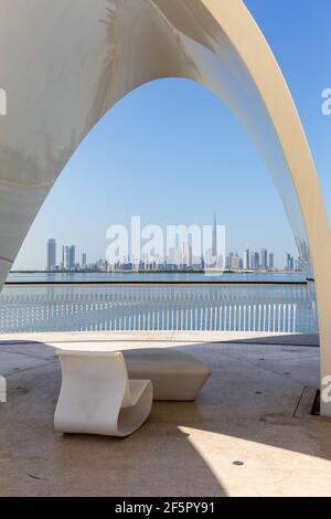 Dubai, VAE, 22,02.2021. Moderner Stuhl mit Sydney Opera House Dach an einer Promenade mit Blick auf Dubai Downtown mit Burj Khalifa Gebäude und Dubai Stockfoto