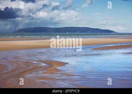 Penmaenmawr Beach, in der Nähe der Stadt Penmaenmawr in Nord-Wales, ist ein langer Sandstrand neben der Menai Straits. Stockfoto