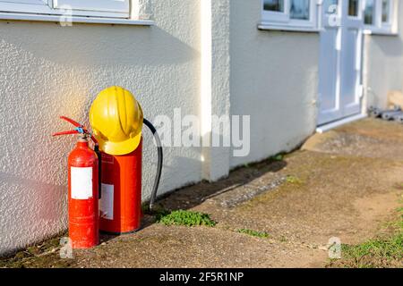 2 Feuerlöscher mit Schutzhelm. Brandschutz, Baustelle, Gebäudekonzept Stockfoto