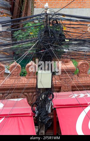 Ein Kabel, das am Elektromast befestigt ist. Das Chaos von Kabeln und Drähten an einem elektrischen Mast, Phnom Penh, Kambodscha. Stockfoto