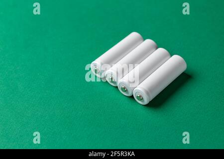 Wiederaufladbare AAA-Batterien in Weiß auf grünem Hintergrund. Für Text platzieren. Konzept der grünen Energie. Stockfoto
