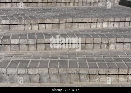 Reihen von grauen Stufen von grauen Pflasterplatten gleichmäßig, konsequent und eng aufeinander gelegt. Stockfoto