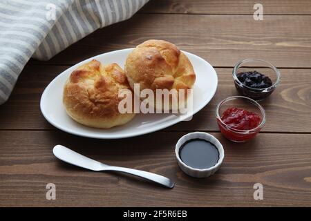 Butterbrotrolle auf einem Teller mit Erdbeermarmelade auf Holztisch Stockfoto