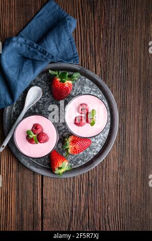 Gesunder Drink, Erdbeer- und Himbeer-Smoothie mit griechischem Joghurt im Glas auf rustikalem Holzhintergrund Stockfoto