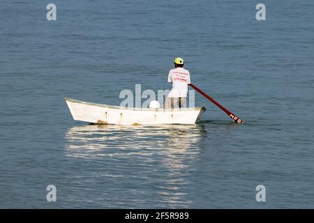 Eingeflügelter Fischer auf dem Meer - in einem kleinen weißen Fischerboot in Mexiko stehen und paddeln Stockfoto