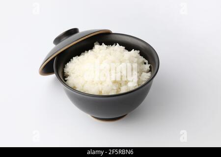 Weißer Reis in Schüssel mit Essstäbchen isoliert auf weiß Hintergrund Stockfoto