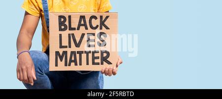 Nahaufnahme einer nicht erkennbaren Person, die ein Banner mit dem Slogan „Black Lives Matter“ hält. Es ist auf blauem Hintergrund isoliert. Leerzeichen für Text. Stockfoto