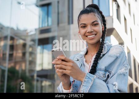 Schöne lächelnde afroamerikanische Frau mit Handy, Online-Shopping, Blick auf die Kamera Stockfoto