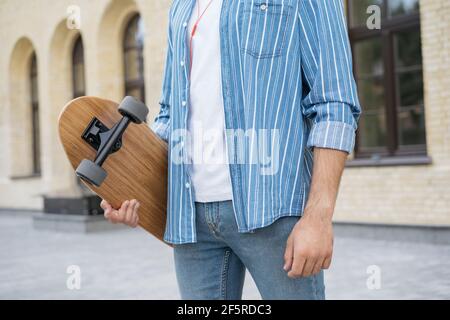 Stilvoller Mann Skater hält Longboard, zu Fuß auf der Straße Stockfoto