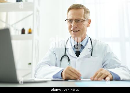 Fröhlich männlichen Arzt mit modernen Laptop bei der Arbeit Stockfoto