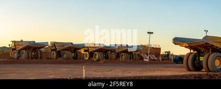 Dump Trucks Reihen sich bei Sonnenuntergang auf Go Line im Tagebaugebiet an. Stockfoto