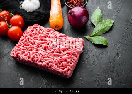 Zutaten zum Kochen Bolognese Sauce, Hackfleisch Fleisch Tomaten und Kräuter Set, auf schwarzem Stein Hintergrund Stockfoto