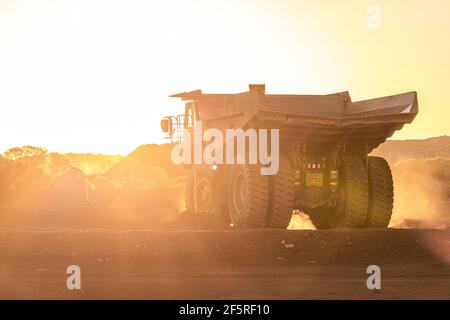 Muldenkipper bei Sonnenuntergang auf der Mining Go Line im Tagebaugebiet. Stockfoto