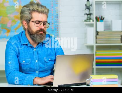 Serious Student mit Notebook studieren in der Hochschule. Bärtiger Lehrer mit Laptop im Klassenzimmer. Stockfoto