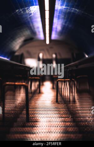 Eine lange schmale eiserne Treppe, die sich tief unterirdisch zu einer U-Bahn-Station Plattform als Hilfsweg zwischen zwei Rolltreppen erstreckt, geringe Tiefe des Fis Stockfoto