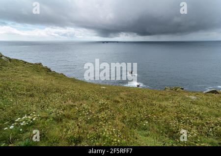 Ein stürmischer, regnerischer Tag mit Blick in den Atlantik zum Leuchtturm von Longships von Land's End in Cornwall, England. Stockfoto