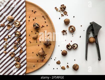 Geknackte Walnüsse auf einem Holzbrett und weißem Hintergrund mit nussknacker Stockfoto