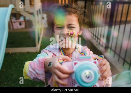 Lächelndes Mädchen spielt mit Blasen im Hinterhof Stockfoto