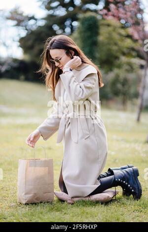 Lächelnde Frau Verbraucher halten Handwerk Tasche im Park vorhanden Stockfoto