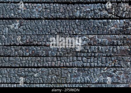 Verbrannter Holzbrett Hintergrund. Details der Oberfläche von verkohltem Holz. Stockfoto