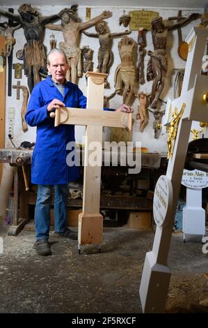 26. März 2021, Sachsen, Neudörfel: Nikolaus Dürlich steht an einem Holzkreuz in seiner Werkstatt. Der sorbische Holzbildhauer ist die dritte Generation, die Kreuze und religiöse Figuren herstellt und restauriert. Foto: Sebastian Kahnert/dpa-Zentralbild/dpa Stockfoto