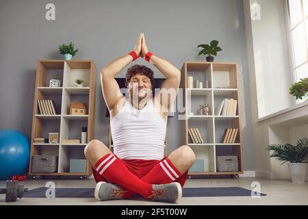 Glücklicher molliger Mann, der Meditation genießt und lächelt im Yoga sitzt Pose zu Hause auf dem Boden Stockfoto