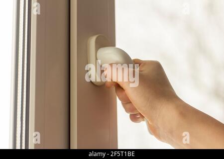 Die Hand des Teenagers öffnet das Fenster, um das auszulüften Zimmer Stockfoto