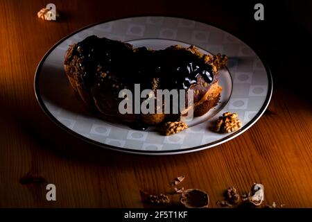 Walnüsse Kuchen von Schokoladensauce auf dem Teller in schwachem Licht. Stockfoto