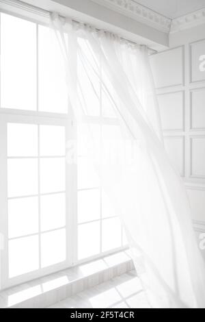 Hintergrundbeleuchtetes Fenster mit weißen Vorhängen im leeren Raum Stockfoto