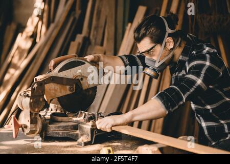 Zimmermann mit elektrischer Holzschneidemaschine mit Schutzsicherheit Ausrüstungen in Holzwerkstatt Stockfoto