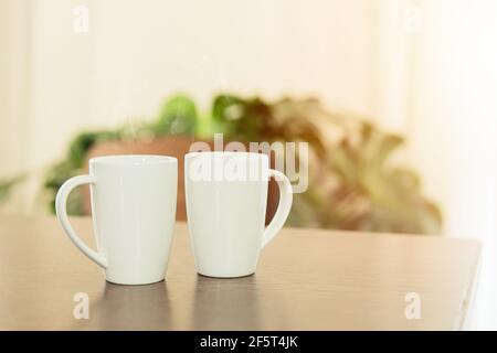 Kaffee am Morgen, zwei weiße Teetasse Tasse auf Holztisch zu Hause platziert. Stockfoto