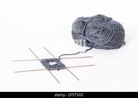 Mit dem Stricken auf vier Stricknadeln beginnen. Strickwolle und Stricknadeln isoliert auf weißem Hintergrund Stockfoto